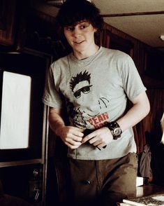 a young man standing in front of a tv holding his hand on his hip and looking at the camera