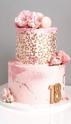 a pink and gold birthday cake with flowers on the top, decorated with leopard print