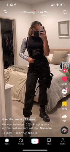 a woman taking a selfie in front of a mirror while wearing black overalls