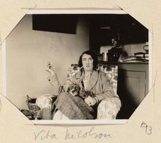 an old black and white photo of a woman sitting in a chair with her dog