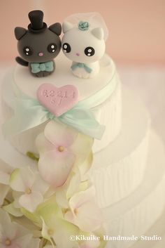 two cats are sitting on top of a wedding cake