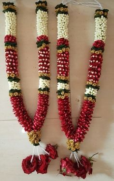 three red and white beads are hanging on the wall next to each other with flowers