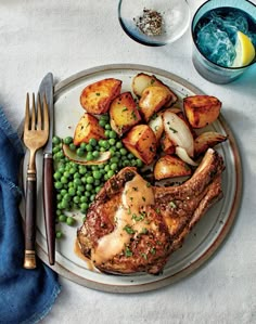 a white plate topped with meat, potatoes and peas