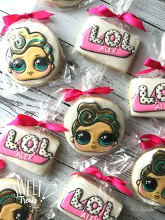 decorated cookies in the shape of lol dolls with bows and ribbons on a table