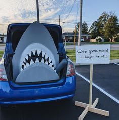 a blue car with a shark's teeth on it and a sign that says were gons need a bigger trunk