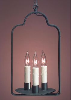 three lit candles hanging from a metal frame