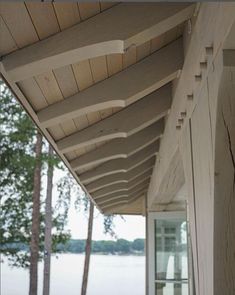 an outside view of a porch with water and trees in the background