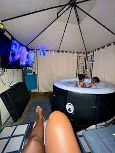 a woman laying in a hot tub with her feet up on the floor and tv