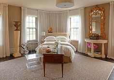 a bed room with a neatly made bed and a table in front of two windows