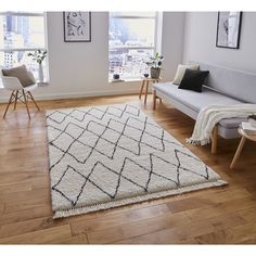 a living room filled with furniture and a white rug on top of a hard wood floor