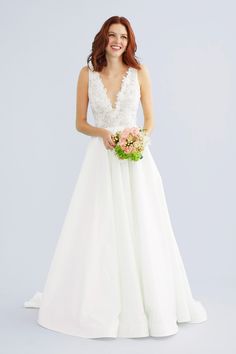 a woman in a white wedding dress holding a flower bouquet and smiling at the camera