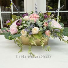 a vase filled with lots of flowers sitting on top of a white table covered in greenery