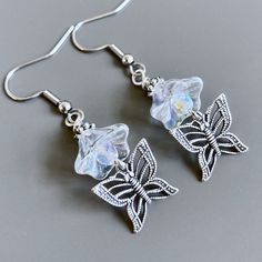 Butterfly Flower Earrings - Antiqued Silver Plated Filigree Butterflies dangle from Clear Crystal Czech Glass Flowers with Silver Plated Beads.  The flowers look like crystals and measure 10mm by 12mm. The earrings measure just under 2" from top of earwires to bottom. Surgical Steel Earwires Whimsical Silver Flower Earrings, Bohemian Silver Butterfly Earrings, Silver Whimsical Flower Earrings, Whimsical Silver Dangle Flower Earrings, Whimsical Silver Flower Earrings With Ear Wire, Whimsical Butterfly Earrings With Ear Wire, Spring Butterfly Charm Jewelry Gift, Summer Butterfly Charm Earrings For Gift, Whimsical White Butterfly Jewelry