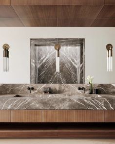 a bathroom with marble counter tops and two sinks in front of a mirror on the wall