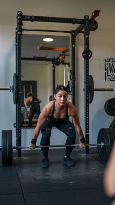 a man squatting down in front of a barbell