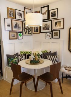 a dining room table with chairs and pictures on the wall above it in a home