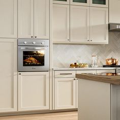 a kitchen with white cabinets and an oven in the center, along with a wooden countertop