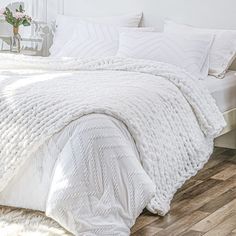 a white bed sitting on top of a wooden floor