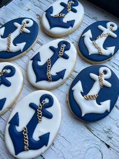 blue and white decorated cookies with gold chains on them are sitting on a wooden table