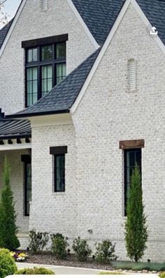 a white brick house with black shingles and windows