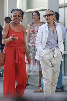 two women walking down the street in front of some people and one is holding her hand