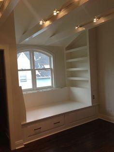 an empty room with white shelves and lights on the ceiling, along with dark wood flooring