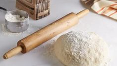 a rolling pin and dough on a table with other baking supplies including flour, salt and pepper shakers