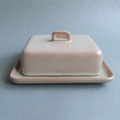 a white ceramic covered dish on a blue surface