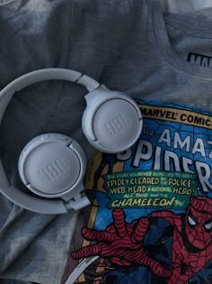 the headphones are laying on top of an open comic book next to earbuds