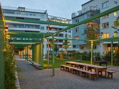 an outdoor area with benches and tables in the foreground, surrounded by apartment buildings