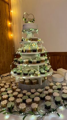 a cake and cupcakes are arranged on a table with lights in the background