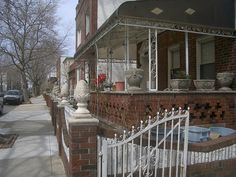 an iron fence is in front of a brick building with potted plants on it