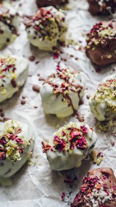 several desserts with white frosting and sprinkles on top of paper