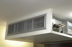 an air conditioner sitting on top of a white shelf in a room with lights