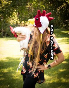 a woman with long hair holding a chicken on her head while standing in the grass