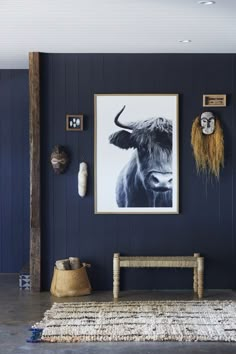 a room with blue walls and artwork on the wall, including a cow's head