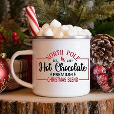 a white mug filled with hot chocolate and marshmallows on top of a wooden table