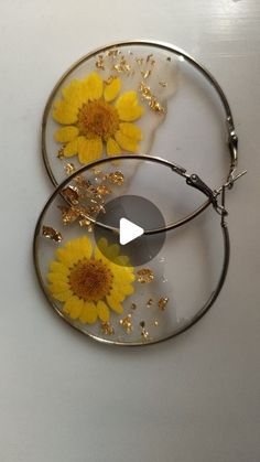 two glass plates with yellow flowers in them on a white counter top, one is holding a pair of scissors and the other has gold flakes attached to it