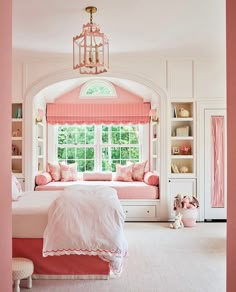 a bedroom with pink walls and white furniture in the corner, along with a window seat