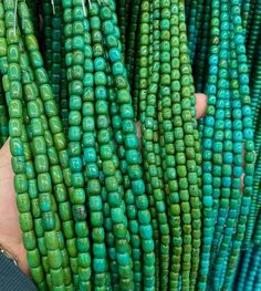 a person is holding some green beads in their hands and they are all different colors