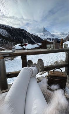 a dog laying on top of a white couch next to a wooden fence with mountains in the background