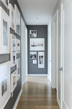 a long hallway with pictures on the wall and wood flooring in front of it