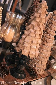 some pine cones are sitting on a table next to candles and other items in front of them