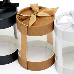 three gift boxes with ribbons and bows on the top one is black, one is white