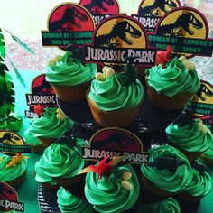 cupcakes with green frosting are stacked on top of each other in front of dinosaur park signs