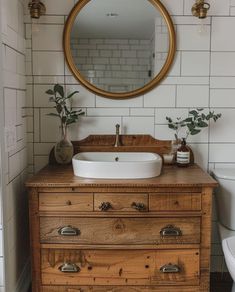 a bathroom with a sink, mirror and wooden dresser in the corner next to a toilet