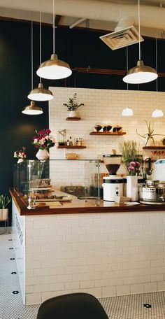 the interior of a restaurant with lights hanging from the ceiling and potted plants on the counter