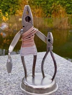 a sculpture of a person holding scissors on top of a table next to a body of water