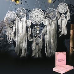 there are many white dream catchers hanging on the wall next to a pink box