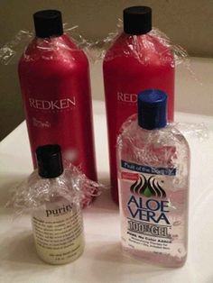 two bottles of aloe vera and redken on a white counter top with plastic wrap around them